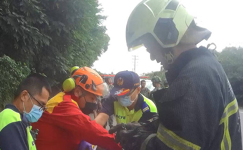 1輛自轎車不明原因擦撞路旁軍方交管人員後撞向邊坡，消防人員協助2人脫困後分別送醫。（新竹縣消防局提供）