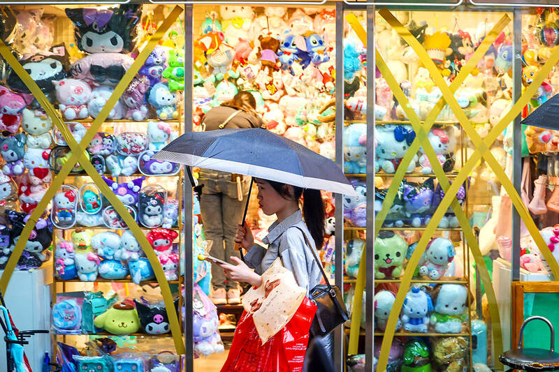 
A person walks past a store in Taipei’s Ximending area with taped-up windows as a precaution for Typhoon Krathon on Oct. 3.
Photo: CNA