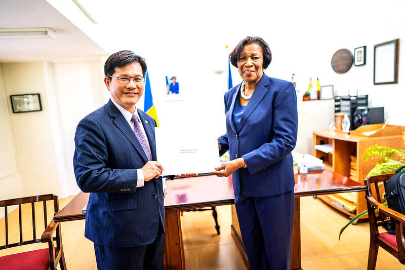 
Minister of Foreign Affairs Lin Chia-lung, left, presents Saint Vincent and the Grenadines Governor-General Susan Dougan with a congratulatory letter from President William Lai on the Caribbean ally’s 45th Independence Day at Dougan’s residence on Saturday. 
Photo: screen grab from Lin Chia-lung’s Facebook page