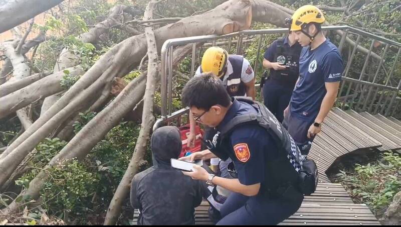 郭男（黑衣套頭者）在柴山上躲了2天多，今早從草叢中走出，被山友發現，警消人員於龍門亭旁木棧道將人帶下山。（民眾提供）