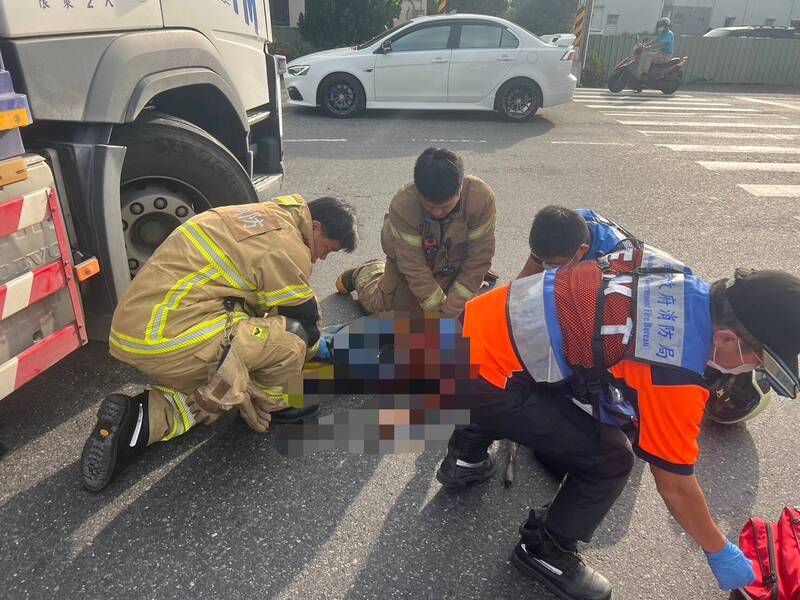 單車女騎士捲入大貨車底，消防隊員全力搶救。（民眾提供）