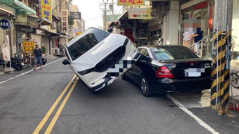 彰化縣和美鎮鬧區出現街頭奇景，白色馬自達休旅車「騎上」黑色賓士車。 （民眾提供）