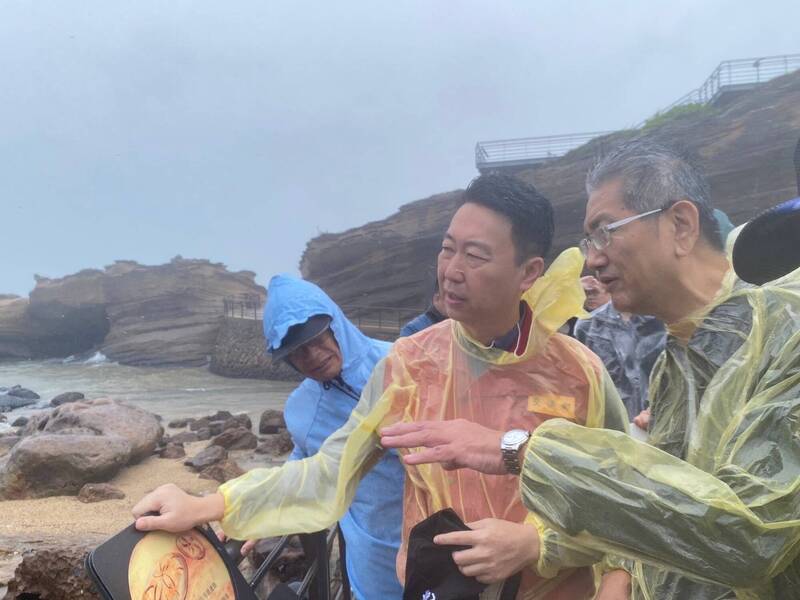 交通部長陳世凱（中）冒風雨到野柳地質公園岸邊，了解擱淺貨輪「鈺洲啟航」應變處置。（圖由航港局提供）