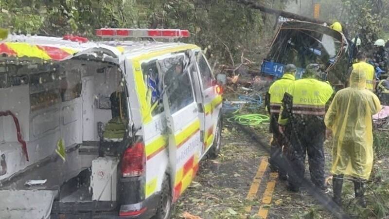 南投縣仁愛鄉台14甲0.1k處，1輛藍色小貨車遭路樹壓毀，車內有2人，1名56歲女子受傷送醫不治，圖為消防人員將傷者送醫情形。（民眾提供）