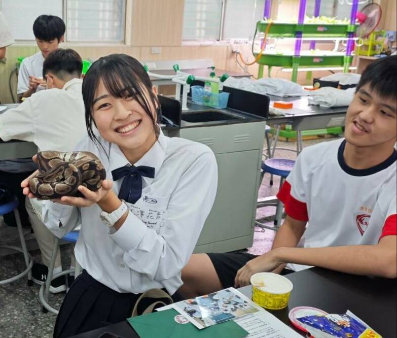 日本福岡高校女學生參加「生物組織切片學習與研究課程」，大膽手捧實驗室蟒蛇開心拍照留念。（鳳山高中提供）