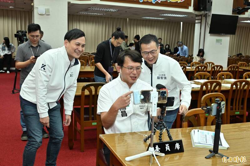 立法院財政委員會今天審議財劃法修正案，藍白陣營聯手讓法案3分鐘救出委員會；圖為民眾黨立委黃國昌（中）在會場架起3支手機開直播，國民黨立委葉元之（左）、羅智強（右）也跟著上鏡。（記者田裕華攝）