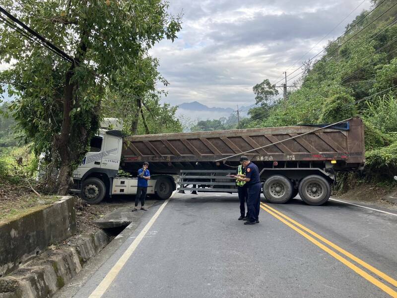 砂石車疑似迴轉不慎，輪子卡在邊溝，擋住路面。（民眾提供）