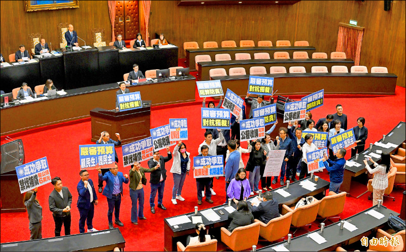 中央政府總預算歷經六度卡關，經朝野七日在行政院會商共識，昨日第七度在立院叩關成功，順利交付委員會審查。國民黨立委在議場內高舉標語，慶賀成功爭取禁伐補償每公頃六萬元等三案。（記者羅沛德攝）