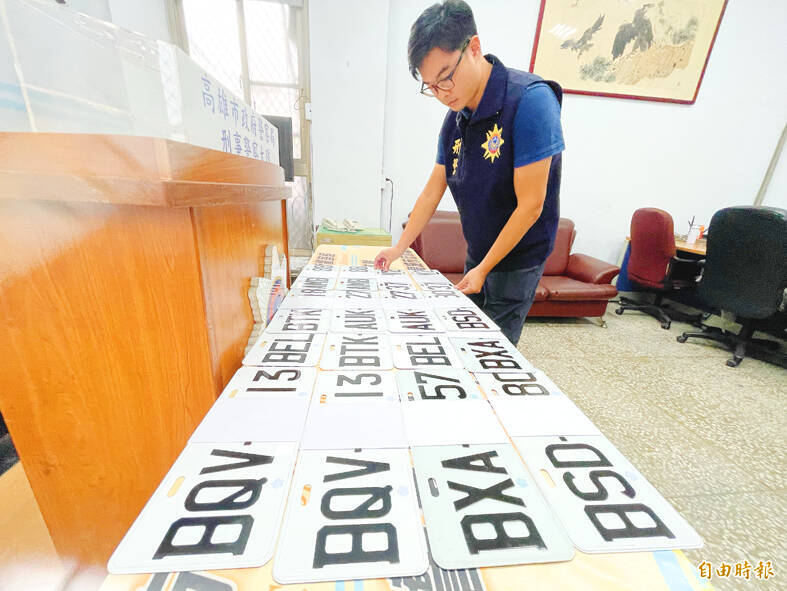 A police officer looks at 16 forged license plates in Kaohsiung on Tuesday.
Photo: Huang Liang-chieh, Taipei Times