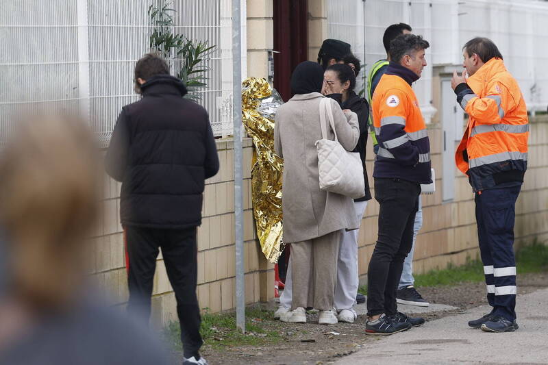 西班牙紧急服务人员与老人的家属15日在事发养老院外等候，其中1人激动掩面。（欧新社）