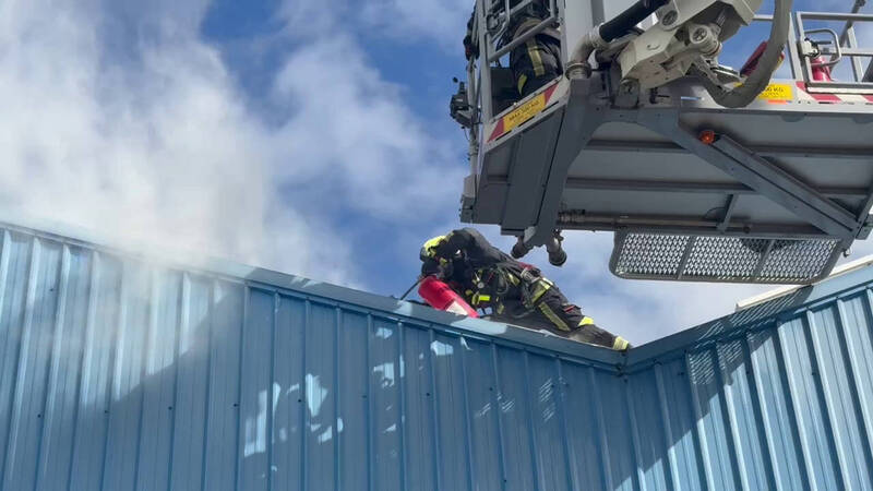 花蓮港口旁一家鐵皮廠房屋頂的光電發電設備今天上午發生火警，由於太陽能板遇光即持續發電，消防人員擔心感電，用乾粉滅火器局部壓制。（消防局提供）