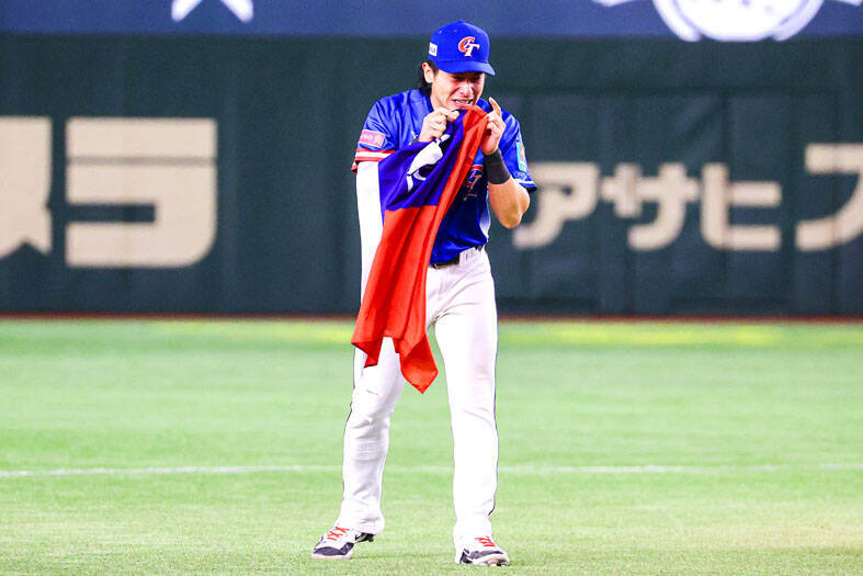 Taiwan’s Chen Chieh-hsien holds the national flag after beating Japan 4-0 to win the World Baseball Softball Confederation’s Premier12 title at the Tokyo Dome on Sunday night.
Photo: CNA