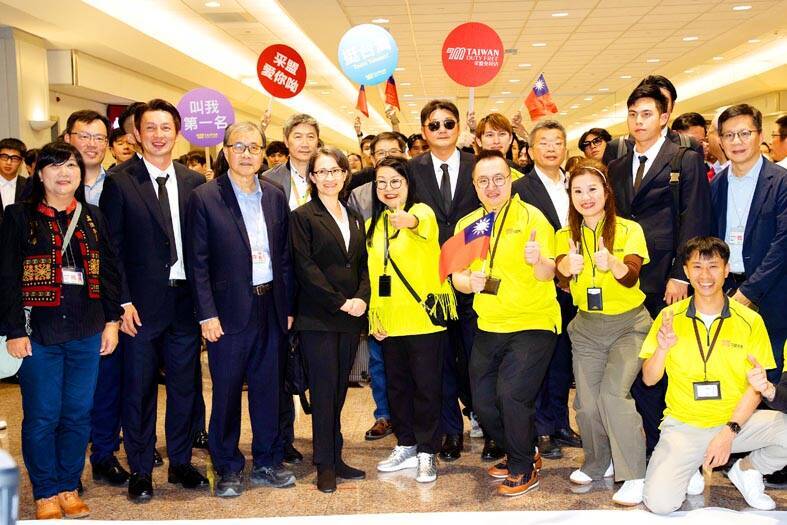 
Tasa Meng employees, wearing yellow, take the prime spot in a photograph with government officials, including Vice President Hsiao Bi-khim, fourth left, and national baseball team players at Taiwan Taoyuan International Airport on Monday.
Photo: CNA