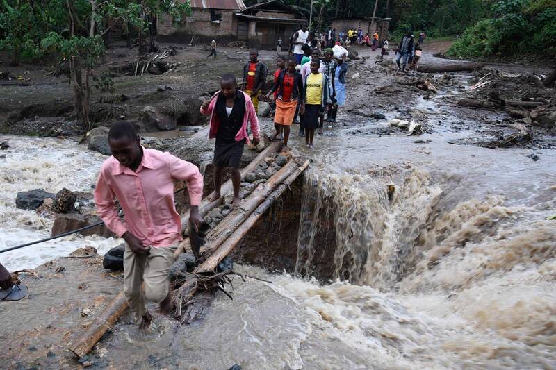 乌干达东部布兰布利区大雨不断导致山崩，至少造成30人死亡。东部另一区2018年10月也曾暴雨酿灾，图为当时民众以木棍石块搭桥过河。（法新社档案照）