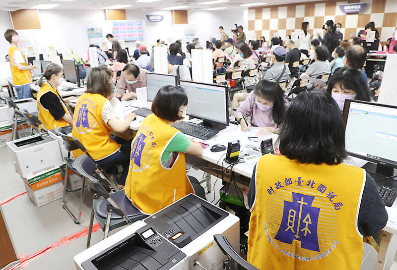 
Taipei National Taxation Bureau employees, wearing yellow vests, help people file tax documents on May 1.
Photo: CNA