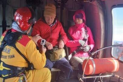 空勤人員將陳姓女山友及詹姓男山友送上直升機，降落東勢河濱公園送醫。（空勤提供）