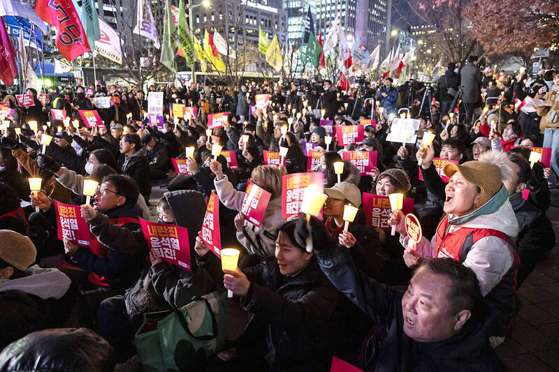 People hold candles and banners, and chant during a protest against South Korean President Yoon Suk-yeol at Gwanghwamun Square in Seoul yesterday.
Photo: Bloomberg