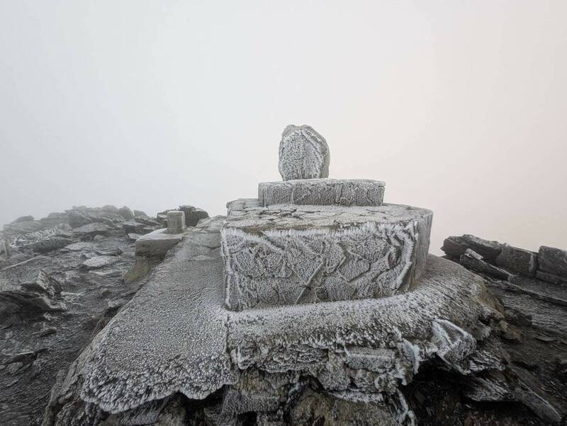 玉山迎來入冬初雪，高山區一片冰封，主峰石碑也結出銀白霧淞，景象「凍」人。（圖由玉管處提供）