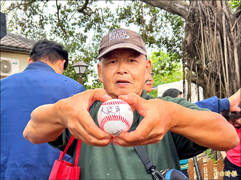 來自東港鎮71歲盛姓民眾開心展示球員的簽名球。（記者羅欣貞攝）