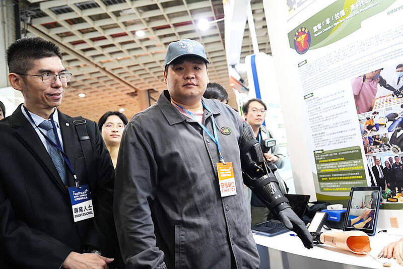 
Sergeant Hung, center, is pictured bionic arm at a medical technology expo at the Nangang Exhibition Center in Taipei on Dec. 5.
Photo: CNA