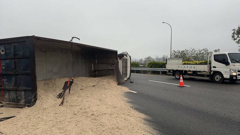 翻覆的砂石車佔據中線、外側及路肩車道，且載運砂土也傾洩一地，導致車流回堵4公里，國道警方已到場引導車流，提醒用路人行經該路段小心慢行。（圖由民眾提供）