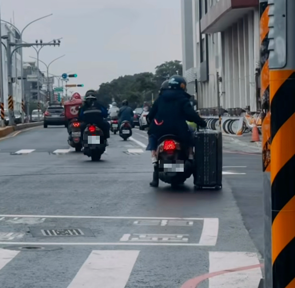 有民眾在台南市區南門路拍下雙載的機車拖拉著一個航空行李箱在馬路上併駛奇景。（圖取自網路）