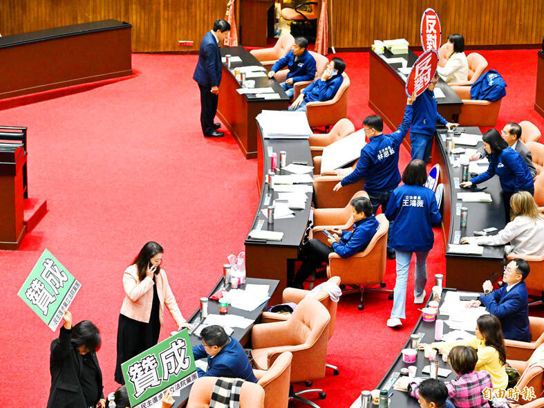 Legislators hold up placards stating their respective stances during a vote at the Legislative Yuan in Taipei yesterday.
Photo: Chen Yi-kuan, Taipei Times