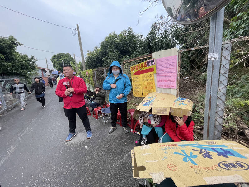 來紫南宮排隊領錢母的民眾遇上小雨，臨時拿紙箱遮雨。（民眾提供）