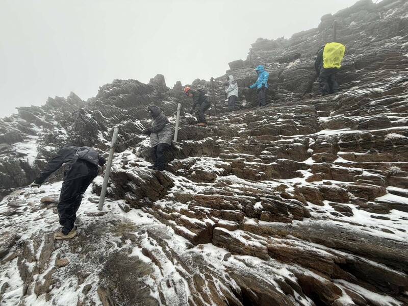 玉山受低溫與水氣影響出現「雨夾霰」，有登頂山友下山遭遇冰霰，只能彎腰抓緊鐵鍊，才能緩緩走下陡坡，場面驚險。（圖由玉管處提供）