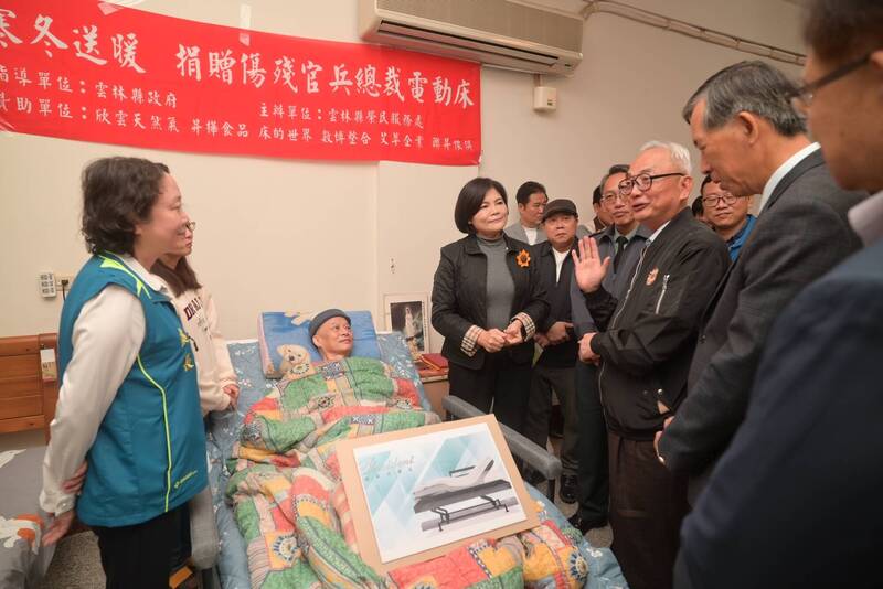 退輔會副主委陳進廣、雲林縣長張麗善、雲林縣榮服處長姚辰蕙、雲林縣民政處長蕭德恕、欣雲天然氣公司董事長林裕盟、昇樺食品董事長吳裕田、數博整合公司董事長張志綸、聯昇傢俱董事長周保谷等人致贈「總裁電動床」給因公重傷的榮民賴筆章。（退輔會提供）