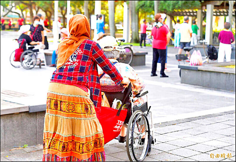 A migrant caregiver pushes a person in a wheelchair in a park in Taipei in an undated photograph.
Photo: Wu Po-hsuan, Taipei Times