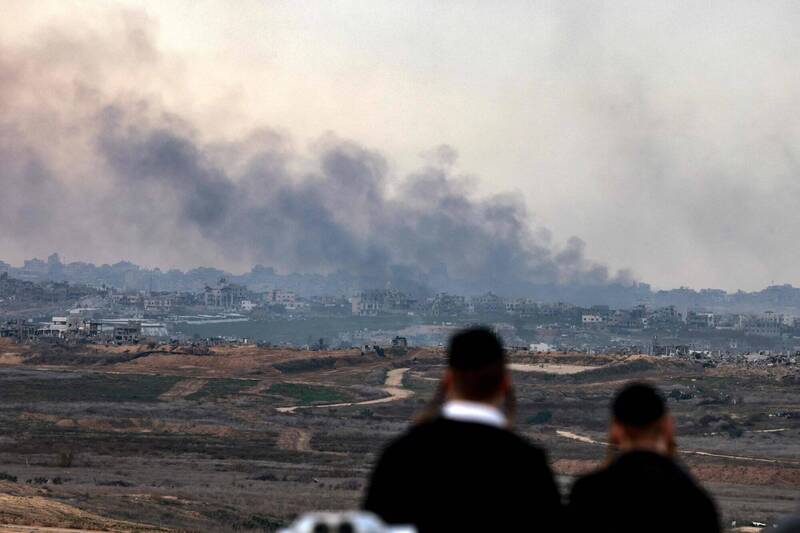 以哈衝突不斷，2名以色列男子5日在南部城鎮史德洛特（Sderot）一座山丘上，目睹以軍轟炸加薩北部地區。（法新社）