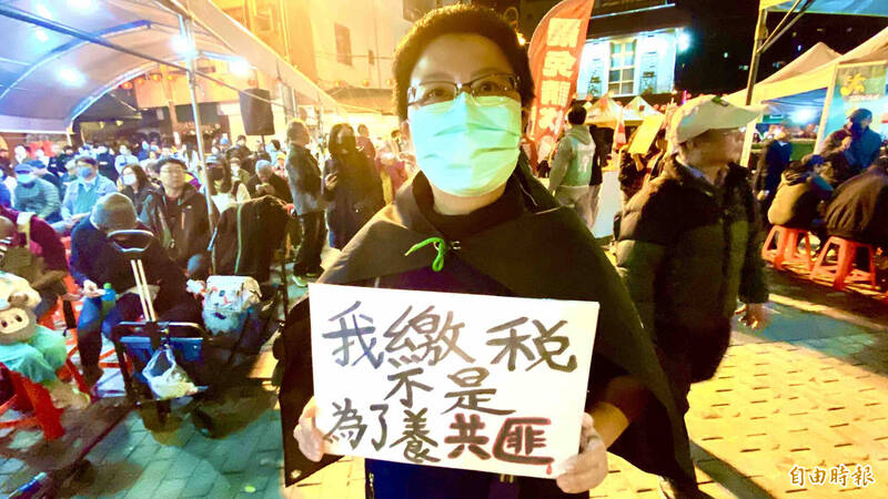 陳小姐舉「我繳稅不是為了養共匪」標語，抗議通匪立委。（記者黃旭磊攝）