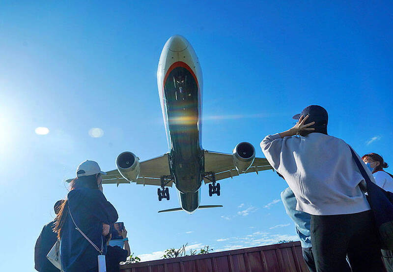 People watch a plane fly over their heads near Taipei International Airport （Songshan airport） on Jan. 19 last year.
Photo: CNA