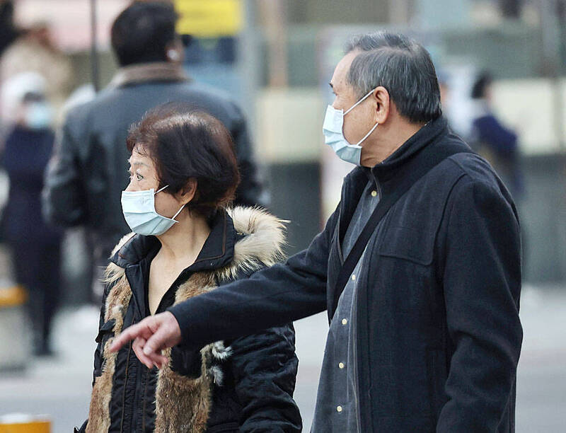 Pedestrians wearing masks walk along a street in Taipei’s Ximending area yesterday. 
Photo: CNA