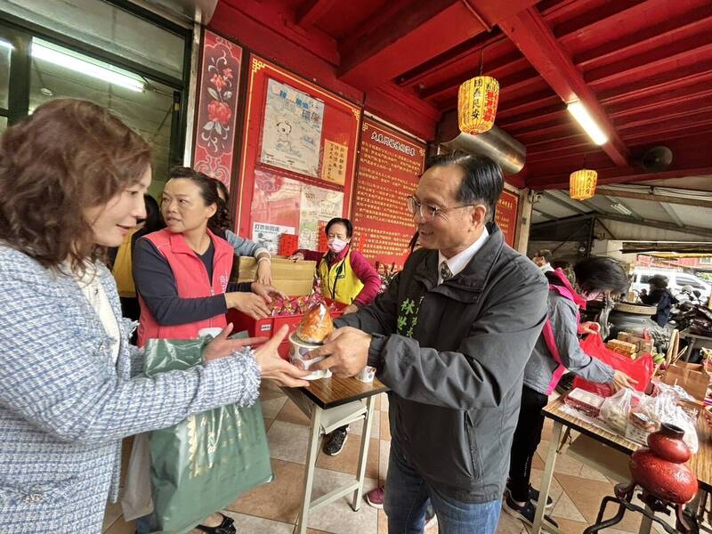 彰化市長林世賢(右)分發麻油雞酒與壽桃給信眾享用。(圖由市公所提供) 彰化市長林世賢(右)分發麻油雞酒與壽桃給信眾享用。(圖由市公所提供)