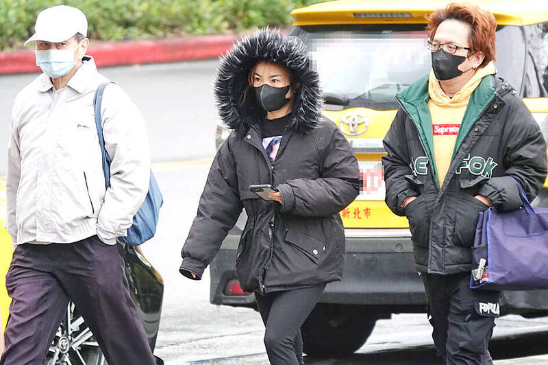 
People in winter clothing cross a street in Taipei yesterday.
Photo: CNA