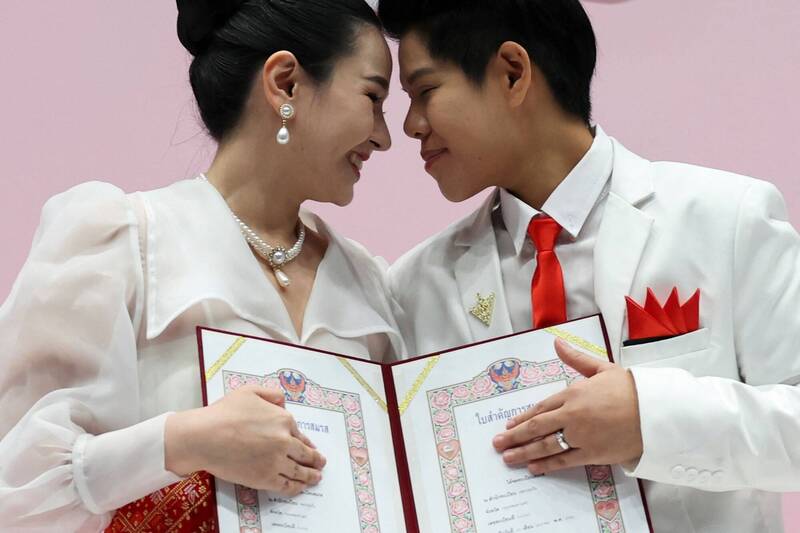 泰國一對 LGBTQ+ 伴侶 Ploynaplus Chirasukon（33歲）和 Kwanporn Kongpetch（32歲）23日收到正式的婚姻證書後合影留念。（路透）