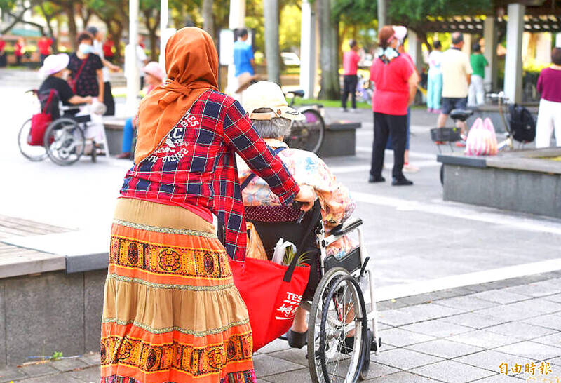 A migrant caregiver attends to an elderly person in a park in Taipei in an undated photograph.
Photo: Taipei Times