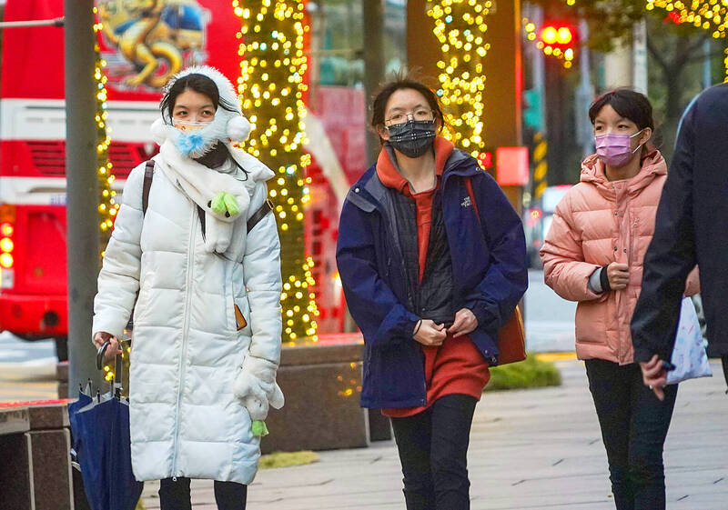 People in winter clothing walk on a street in Taipei yesterday.
Photo: CNA People in winter clothing walk on a street in Taipei yesterday.
Photo: CNA
