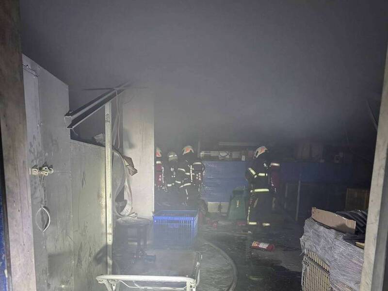 伸港鄉一間五金工廠今天下午發生火災，火場濃煙密布，消防員搶進火場搶救。 （消防局提供）