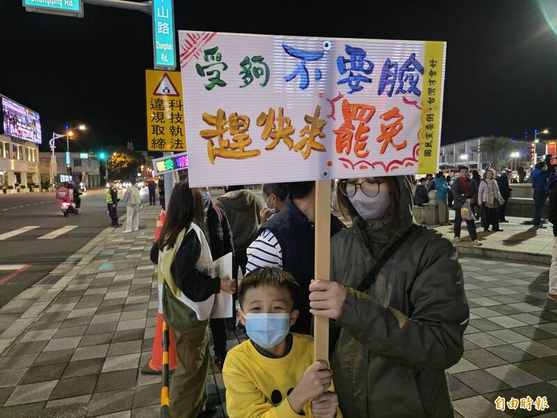 媽媽帶小孩拿著罷免看板站在街頭。（記者花孟璟攝）