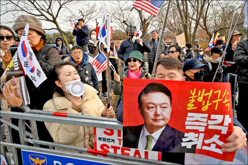 尹錫悅支持者舉起寫有「立即撤銷非法逮捕令」的牌子，高聲為尹加油。（法新社）