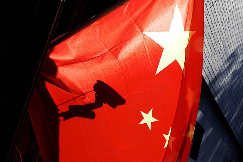 A surveillance camera is silhouetted behind a Chinese national flag in Beijing on Nov. 3, 2022.
Photo: Reuters A surveillance camera is silhouetted behind a Chinese national flag in Beijing on Nov. 3, 2022.
Photo: Reuters