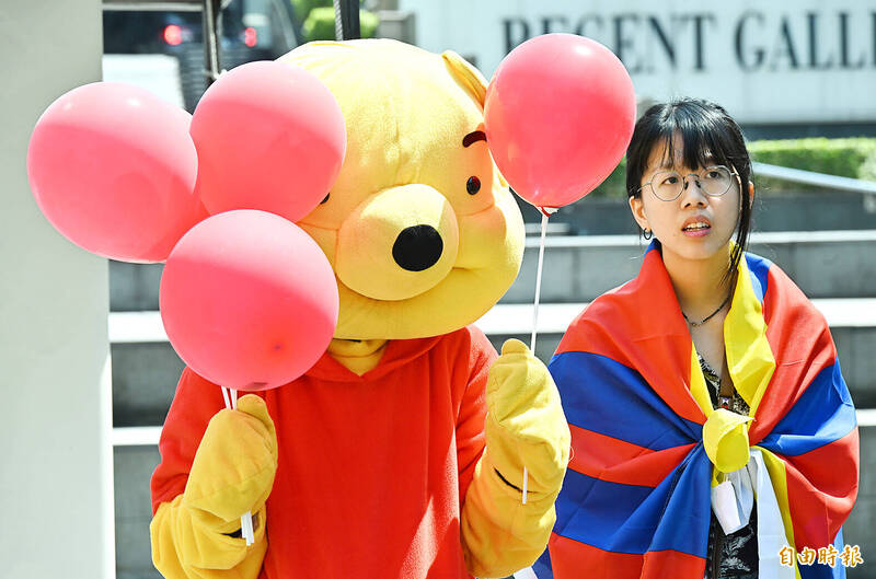 A protester dressed as Winnie the Pooh holds balloons next to a woman wrapped in a Tibetan flag in Taipei yesterday during a protest marking the anniversary of the implementation of Article 23 of the Hong Kong Basic Law.
Photo: Tien Yu-hua, Taipei Times
A protester dressed as Winnie the Pooh holds balloons next to a woman wrapped in a Tibetan flag in Taipei yesterday during a protest marking the anniversary of the implementation of Article 23 of the Hong Kong Basic Law.
Photo: Tien Yu-hua, Taipei Times