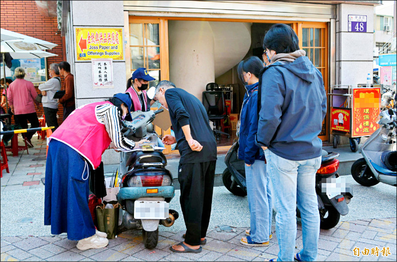 台中民間團體推動罷免國民黨立委羅廷瑋，昨克難在機車坐墊上填寫連署單。（記者陳建志攝）