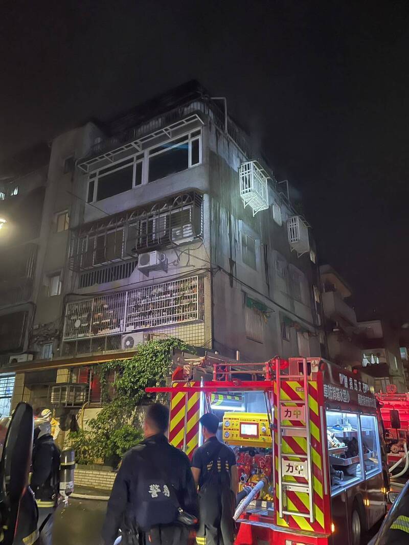 台北市信義區嘉興街舊公寓大樓頂加深夜惡火，消防人員漏夜灌救。（記者邱俊福翻攝）
