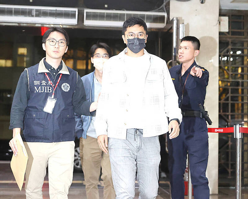 
Ministry of Justice Investigation Bureau agents escort Chinese Nationalist Party （KMT） Youth League member Lee Hsiao-liang, front right, at the Taipei District Prosecutors’ Office for questioning last night.
Photo: CNA
