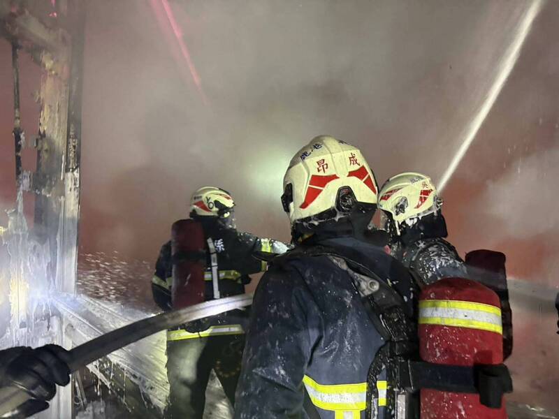 彰化縣福興鄉倉庫深夜大火濃煙密布，消防員部署水線灌救。（彰化縣消防局提供）