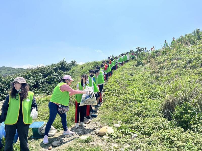 少年團組成接力隊伍,合作將一袋袋垃圾送至上方道路。(新北少年培力園提供) 少年團組成接力隊伍,合作將一袋袋垃圾送至上方道路。(新北少年培力園提供)
